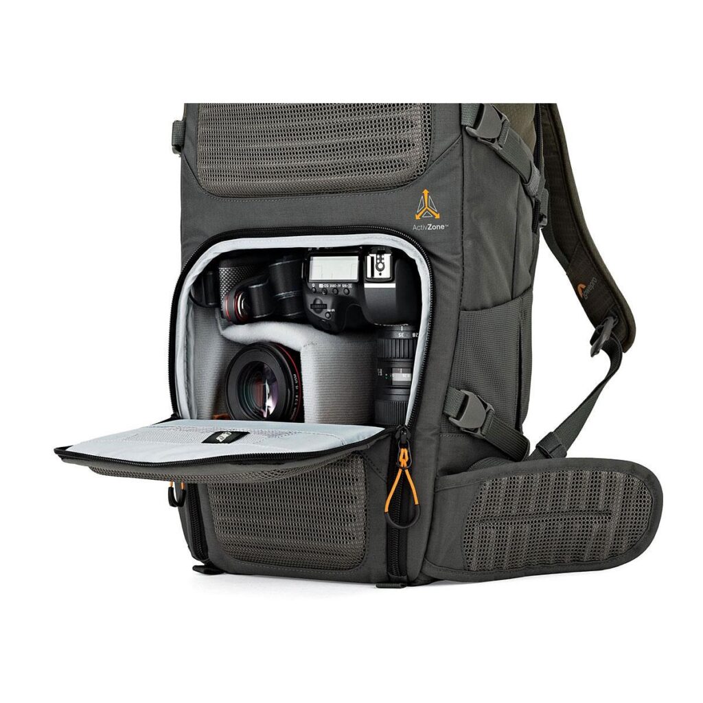 Lowepro_Flipside_Trek_350_001 Harmaassa kuvassa näkyvän Lowepro Flipside Trek 350 -kamerareppu on etuläppä auki, ja siinä on DSLR-kamera, kaksi objektiivia, lisälokeroita lisävarusteille, pehmustetut hihnat ja verkkotaskut.