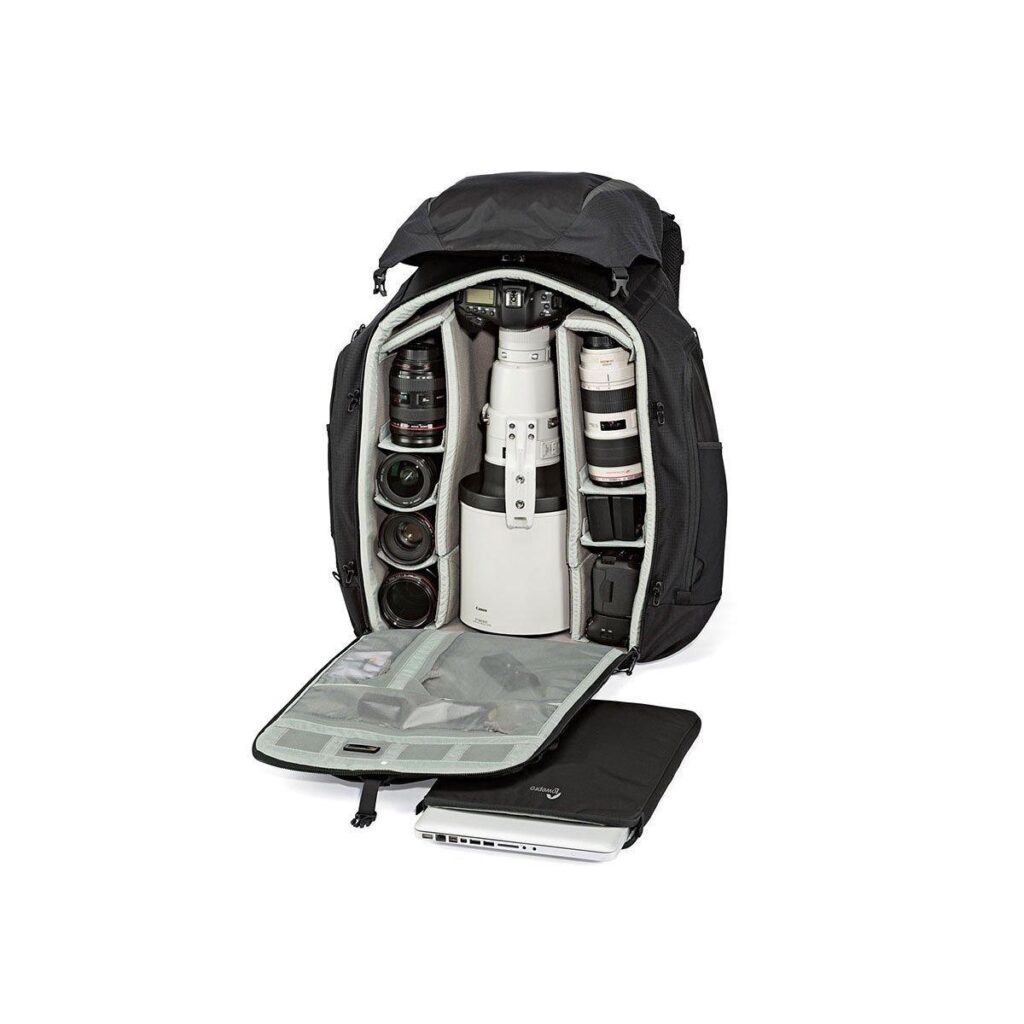 Lowepro_Pro_Trekker_650_AW_001 Lowepro Pro Trekker 650 AW -kamerareppu on auki, ja siinä näkyy järjestäytyneet lokerot, joissa on useita objektiiveja, suuri teleobjektiivi, tarvikkeet etuläpän sisällä ja osittain näkyvä kannettava tietokone laukun vieressä.