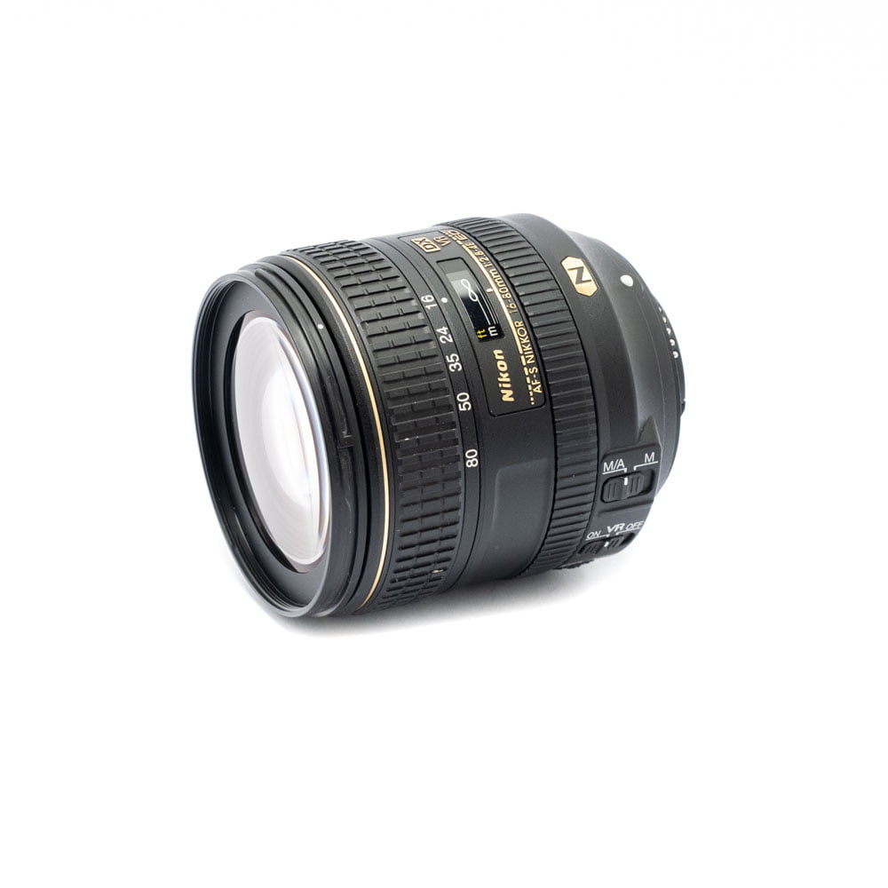 Nikon Z6 II (Kunto K5, Takuuta 22kk, Shuttercount 1100) - Käytetty kamera, jossa on kullanvärinen ja valkoinen teksti mustalla objektiivirungolla valkoisella pohjalla, ja jossa on näkyvät kytkimet ja zoomausmerkinnät.