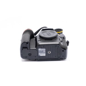 Nikon Z6 II (Kunto K5, Takuuta 22kk, Shuttercount 1100) - Käytetty kamerarunko on kuvassa selkäpuolella objektiivin kiinnitys ylöspäin. Alhaalla näkyy akkulokero, jalustan liitäntä, tuoteseloste ja osittain näkyvä hihna.