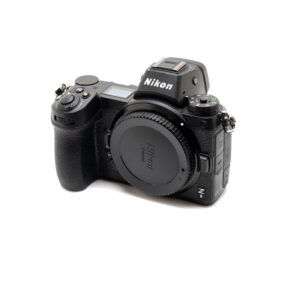 Nikon Z6 II (Kunto K5, Takuuta 22kk, Shuttercount 1100) - Käytetty peilitön kamera, jossa on objektiivin kiinnityssuojus, näkyy valkoista taustaa vasten. Nikonin logo näkyy etsimessä.