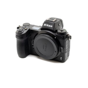 Nikon Z6 II (Kunto K5, Takuuta 22kk, Shuttercount 1100) - Käytetty peilitön kamera, jossa on objektiivin kiinnityssuojus, näkyy valkoista taustaa vasten. Nikonin logo näkyy etsimessä.