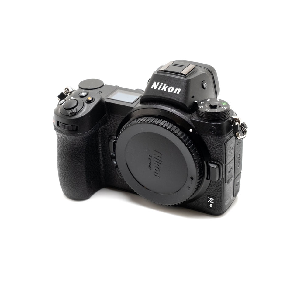 Nikon Z6 II (Kunto K5, Takuuta 22kk, Shuttercount 1100) - Käytetty peilitön kamera, jossa on objektiivin kiinnityssuojus, näkyy valkoista taustaa vasten. Nikonin logo näkyy etsimessä.