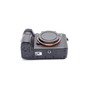 Nikon Z6 II (Kunto K5, Takuuta 22kk, Shuttercount 1100) - Käytetty runko alhaalta kuvattuna, jossa näkyy akkulokero, jalustakiinnitys ja muistikorttipaikka. Objektiivia ei ole kiinnitetty; rungon suojus peittää objektiivin kiinnityksen.