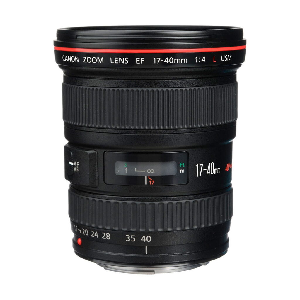Canon EF 17-40mm f/4 L USM -objektiivi, jossa on punainen rengas, tarkennusrengas ja zoomausrengas, etäisyysasteikko ja AF/MF-kytkin, seisoo pystyssä valkoista taustaa vasten.
