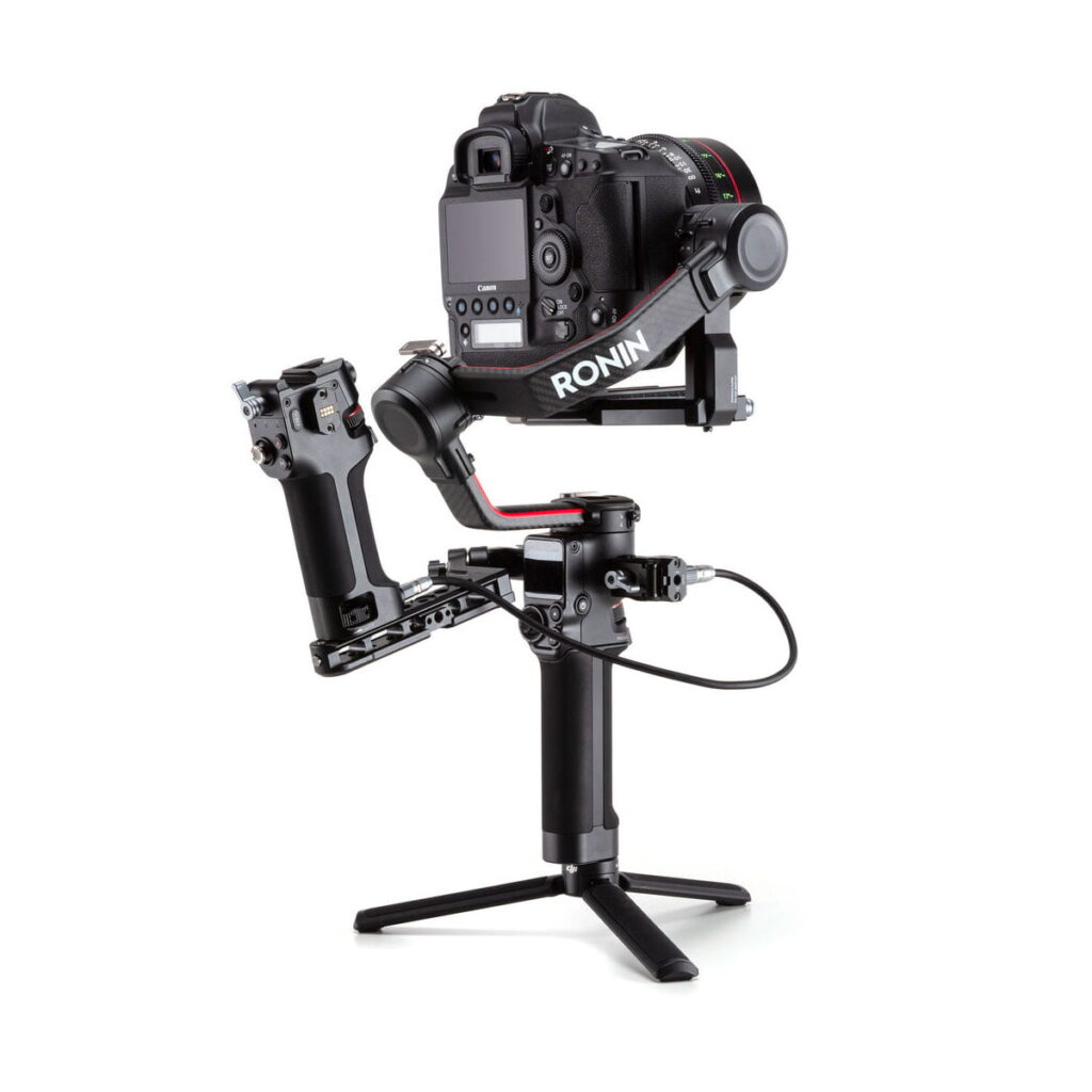DJI-Tethered-Control-Handle-for-RS-2-04 Musta DSLR-kamera on kiinnitetty DJI Tethered Control Handle for RS 2 -ohjauskahvaan jalustan jalat ojennettuina, mikä mahdollistaa vakaan käsivaralta ohjaamisen sujuvia video- ja valokuvauskuvia varten.