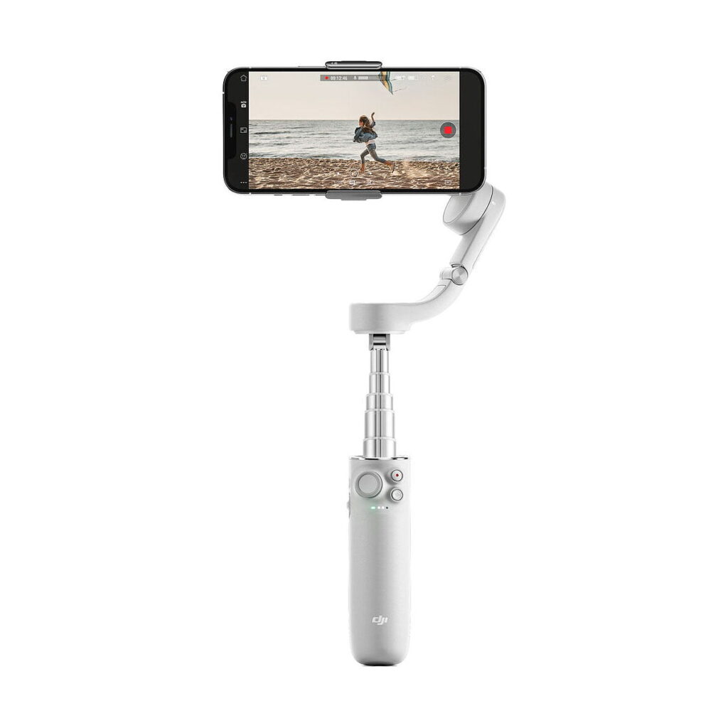 DJi_OM_5_Sunset_Grey_003 Älypuhelin on kiinnitetty DJI OM 5 vakaaja älypuhelimille - Harmaa, kuvassa laajennettu ja tallentava video henkilöstä, joka juoksee rannalla.