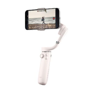 DJi_OM_5_Sunset_White_002 DJI OM 5 vakaaja älypuhelimille - Valkoinen pitää puhelimen vaaka-asennossa ja näyttää videon, jossa henkilö nostaa lasta rannalla meren äärellä.