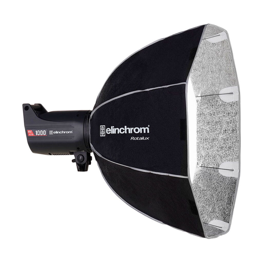 Elinchrom_Rotalux_Deep_Octabox_70cm_003 Studiostroboskooppivalaisin, johon on kiinnitetty suuri musta-hopea Elinchrom Rotalux Deep Octabox 70cm softbox, joka on suunniteltu ammattimaiseen valokuvaukseen.