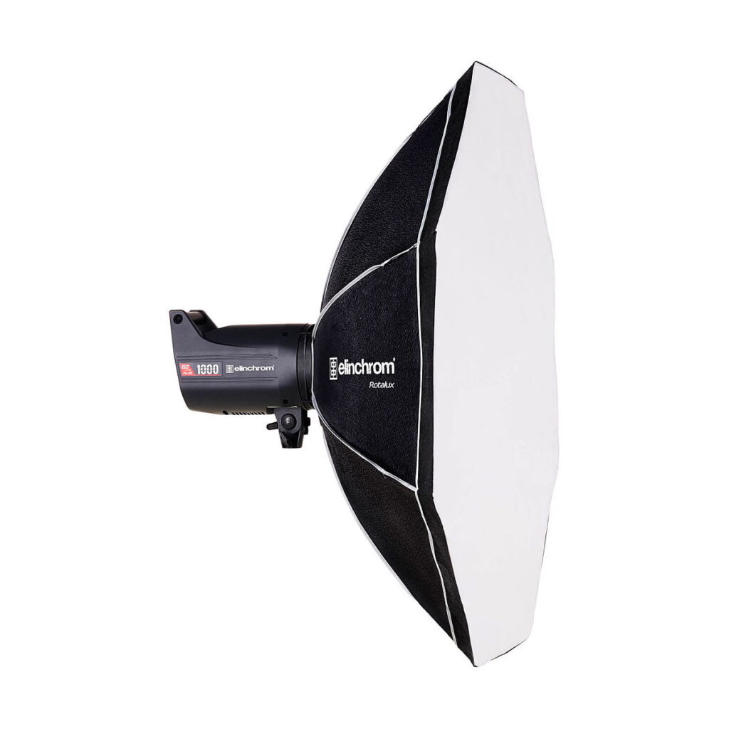 Elinchrom_Rotalux_Octabox_100cm_001 Mustavalkoinen Elinchrom Rotalux Octabox 100cm -studiostrobovalaisin ja siihen liitetty kahdeksankulmainen softbox, sivulta katsottuna valkoista taustaa vasten.