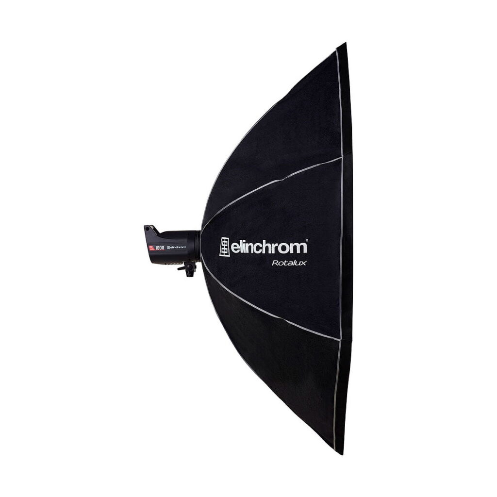 Elinchrom_Rotalux_Octabox_175cm_002 Sivukuva suuresta, mustasta Elinchrom Rotalux Octabox 175cm softboxista, joka on kiinnitetty studiostroboskooppiin, jota käytetään ammattimaiseen valokuvaukseen.