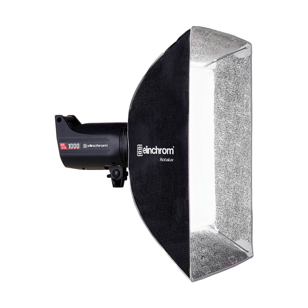 Elinchrom_Rotalux_Squarebox_70cm_003 Elinchrom Rotalux Squarebox 70cm on musta studiostroboskooppivalaisin, jossa on suorakulmainen hopeinen heijastin softbox, joka on suunniteltu ammattimaiseen valokuvaukseen.