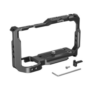 SmallRig_3531_Cage_for_Sony_ZV-E10_003 Kuvassa näkyy mustaa metallia oleva SmallRig Cage for Sony ZV-E10 3531, joka on suunniteltu pitämään kamera tukevasti paikallaan. Kuvassa on myös kiinnitysruuvi, pieni kiinnike, kuusiokoloavain ja pieni ruuvi valkoisella pohjalla.