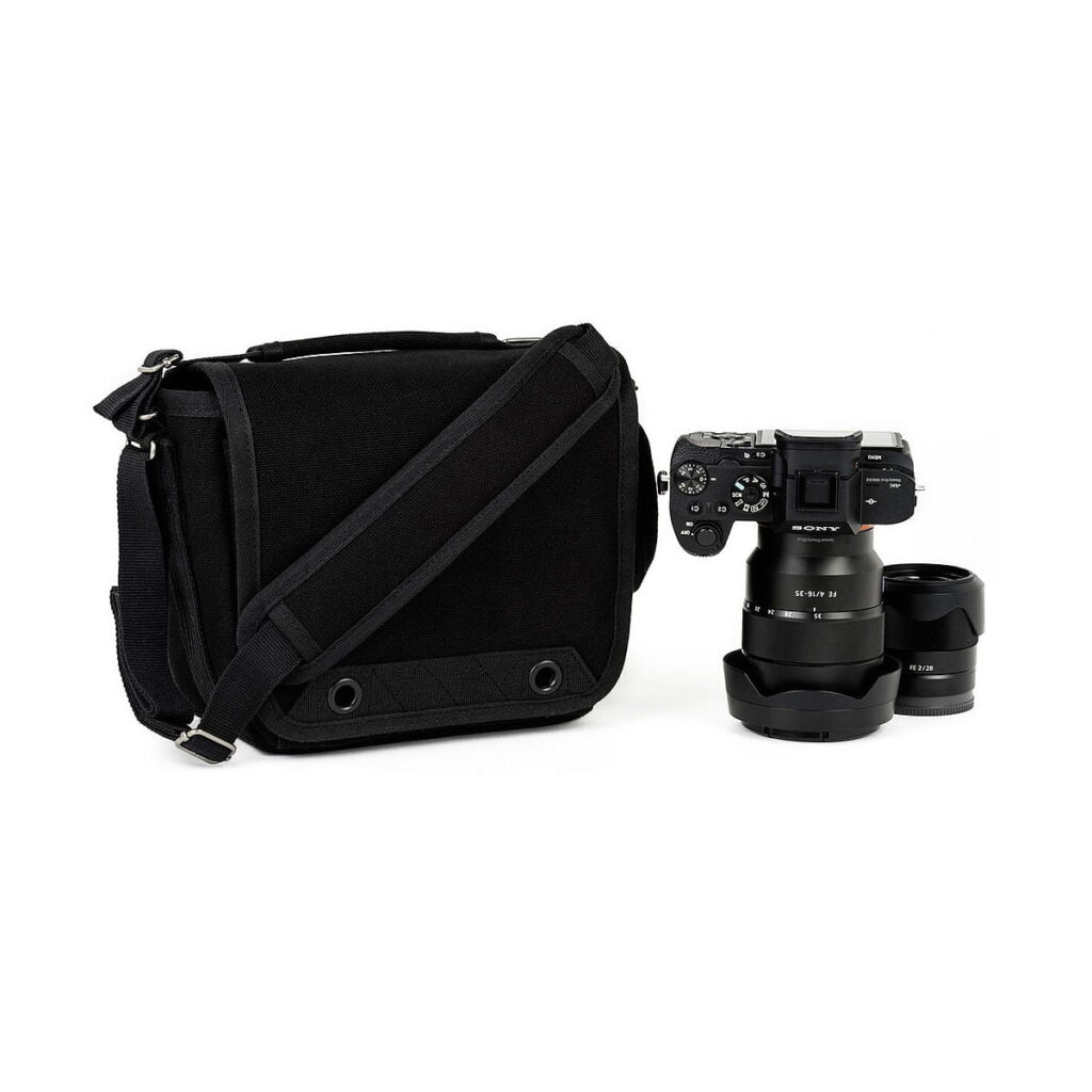 Think_Tank_Retrospective_4_V2_0-Musta_003 Think Tank Retrospective 4 V2.0 - The black camera bag is placed next to the digital camera with the lens attached and an extra lens nearby, all on a white background.