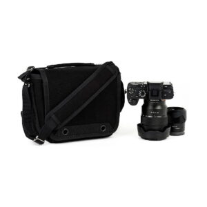 Think_Tank_Retrospective_4_V2_0-Musta_003 Think Tank Retrospective 4 V2.0 - The black camera bag is placed next to the digital camera with the lens attached and an extra lens nearby, all on a white background.