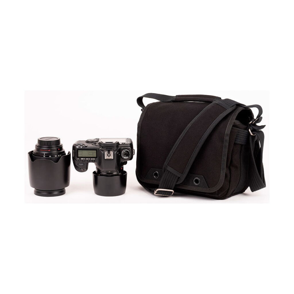 Think_Tank_Retrospective_5_V2_0-Musta_004 Think Tank Retrospective 5 V2.0 - The black camera bag is pictured next to the digital camera with the lens attached and an extra lens with the cover up, all placed on a plain white background.