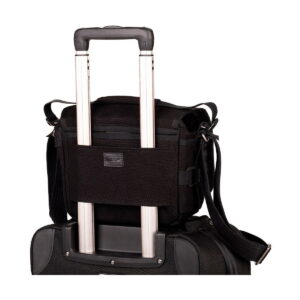 Think_Tank_Retrospective_5_V2_0-Musta_005 Think Tank Retrospective 5 V2.0 - Black, a compact black bag with a shoulder strap is securely attached to the extended handle of a larger roller bag against a white background.
