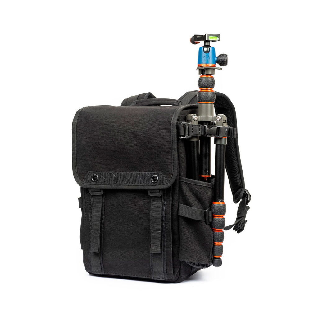 Think_Tank_Retrospective_Backpack_15-Black_006 The Think Tank Retrospective Backpack 15, black with front flap and side pockets, includes a folding tripod with black and orange feet and blue ball head, all against a white background.