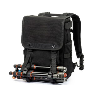 Think_Tank_Retrospective_Backpack_15-Black_007 Think Tank Retrospective Backpack 15, black with padded shoulder straps and front flap, has a tripod attached to the front with two adjustable buckle straps. The background is white.