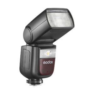 Godox-Ving-V860-III-TTL---Nikon-5 Musta Godox Ving V860 III TTL-salama Nikon-kameroille, jossa on suorakulmainen, ylöspäin taivutettu pää, läpikuultava kansi, ohjauspainikkeet ja jalkajalka, kuvassa valkoista taustaa vasten.