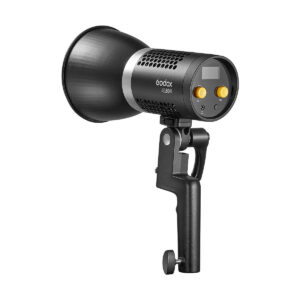 Godox_ML60Bi_Led_videovalo_003 Musta Godox ML60Bi Led videovalo -LED-valo, jossa on kahva, tuuletettu runko, digitaalinen näyttö ja kaksi keltaista säätönuppia valkoista taustaa vasten.