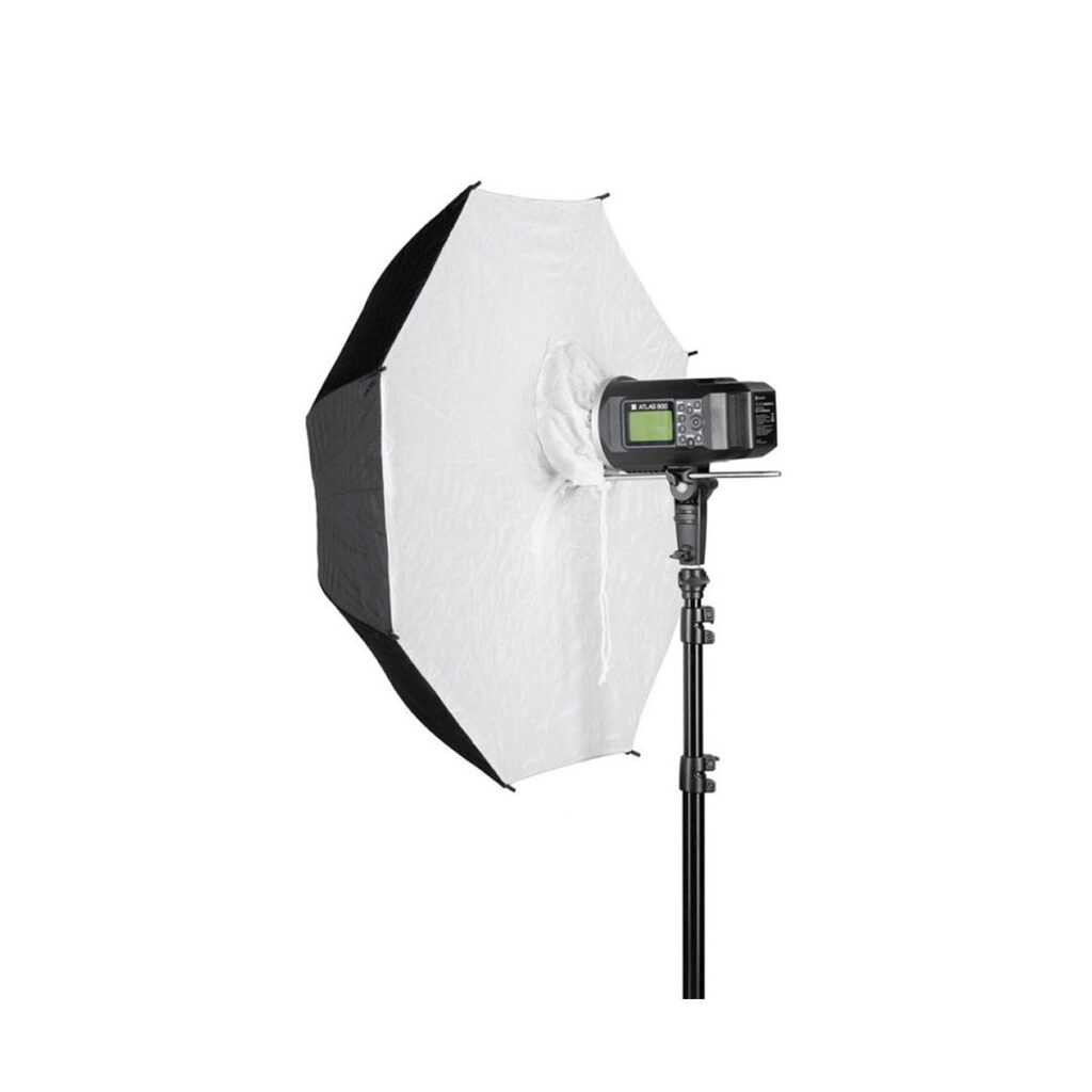 Quadralite_84_White_Umbrella_Softbox_002 Quadralite Umbrella Softbox 84cm on asennettu studiostroboskoopin ja jalustan päälle, ja sen valkoinen ja musta kahdeksankulmainen diffuusori on auki ammattimaista valokuvausvalaistusta varten. Softboxin näyttö on näkyvissä.