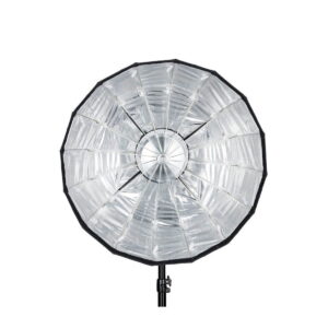 Quadralite_Flex_65cm_Foldable_Beauty-Dish_005 Quadralite Flex 65cm Foldable Beauty-Dish, suuri pyöreä hopeanvärinen softbox, jossa on heijastava sisus, on asennettu mustalle jalustalle ja sitä katsotaan edestä valkoista taustaa vasten.