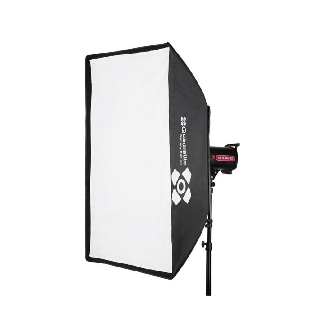 Quadralite_Softbox_120x80cm_001 Quadralite Softbox 120x80cm, jossa on valkoinen diffuusori ja mustat sivut, on asennettu studiovalotelineeseen. Softboxissa on teksti Quadralite ja sen logo.