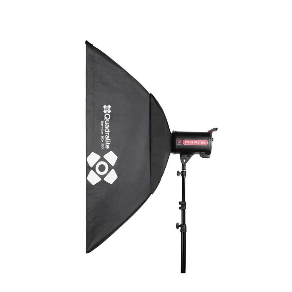 Quadralite_Softbox_120x80cm_002 Quadralite Softbox 120x80cm on kiinnitetty studiostroboskooppivalaisimeen, joka on asennettu mustaan säädettävään jalustaan. Valoyksikössä on merkintä Pulse PRO 600.