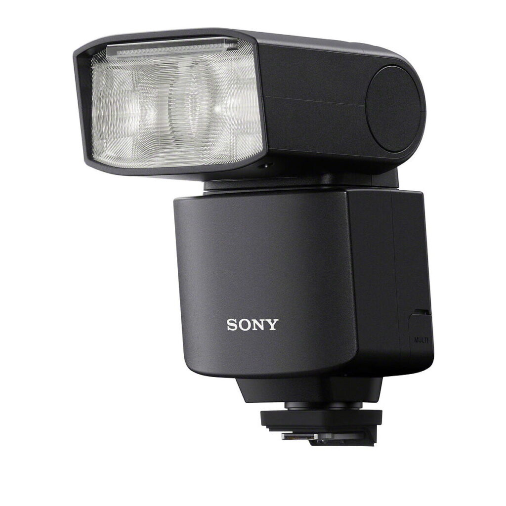 Sony_HVL-F46RM_003 Musta Sony HVL-F46RM -kameran ulkoinen salama, jossa on suorakulmainen, hieman ylöspäin kallistettu pää, on asennettu kuuman kengän jalustalle valkoista taustaa vasten.