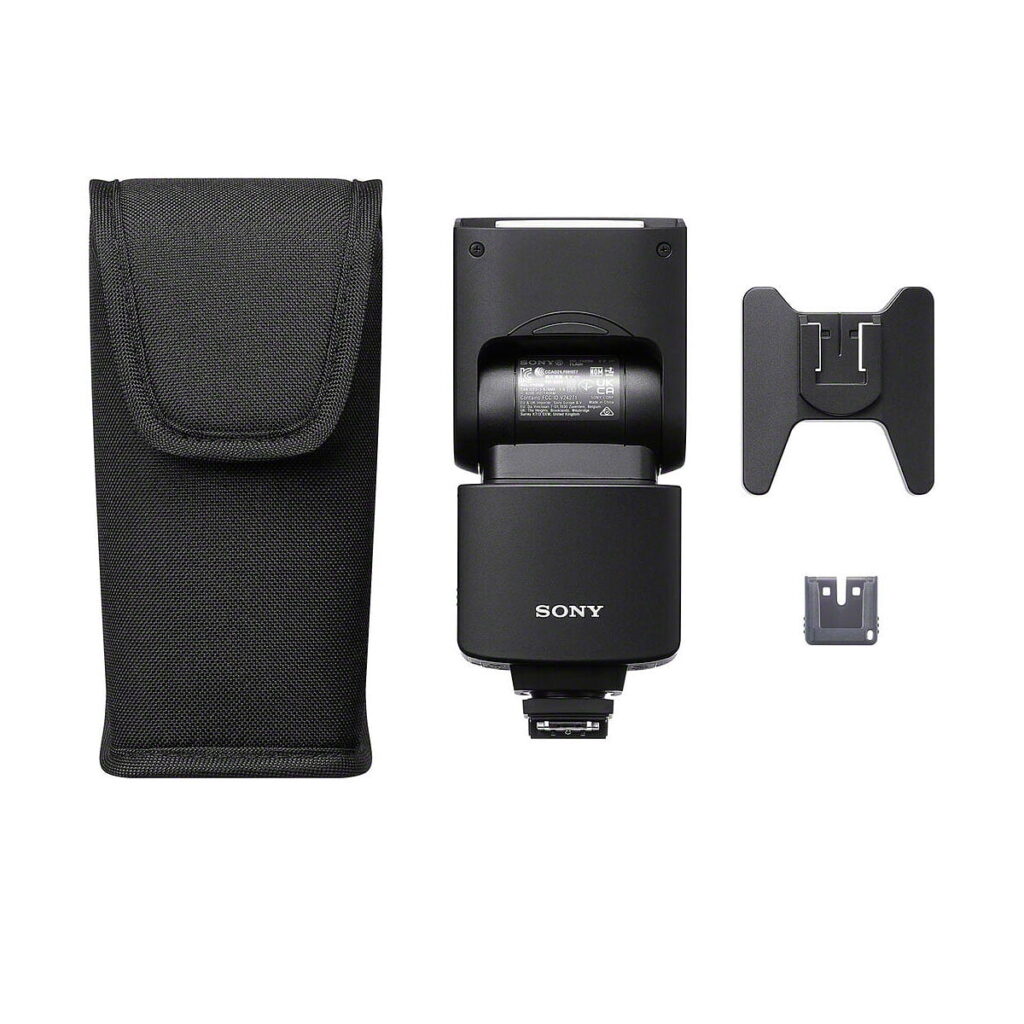 Sony_HVL-F46RM_006 Sony HVL-F46RM -salama, jossa on suojakotelo, leveä diffuusori ja kiinnityssovitin valkoisella pohjalla.