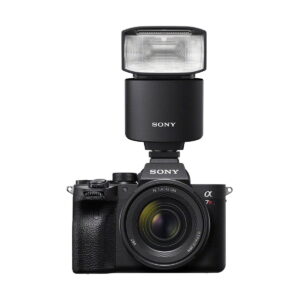 Sony_HVL-F46RM_010 Musta Sony-digitaalikamera, jossa on zoom-objektiivi ja suuri käsisalama, Sony HVL-F46RM, asennettuna päälle, kuvattuna valkoista taustaa vasten.