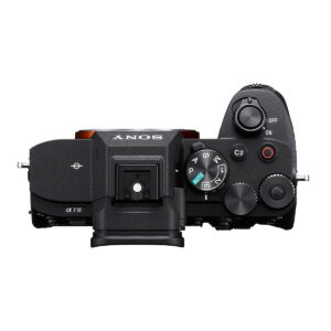 Sony_a7_IV_002 Ylhäältä katsottuna Sony A7 IV -järjestelmäkamera (300€ alennus), jossa on ohjauspyörät, virtakytkin, moodivalitsin, kuumakenkäkiinnitys ja useita painikkeita tyylikkäässä mustassa rungossa.