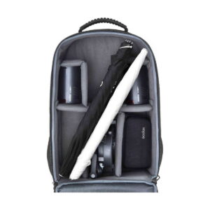 ad100pro_3backpack_03 Avoimessa Godox AD100 Pro TTL 3 salamaa -reppupaketissa, jossa on pehmustetut väliseinät, on kaksi kamerasalamaa, kierrejohto, vetoketjullinen pussi ja taitettu mustavalkoinen sateenvarjo.