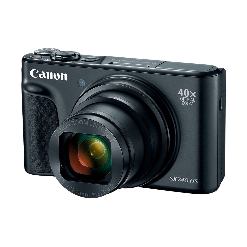 Musta Canon PowerShot SX740 HS -kompaktikamera, jossa on 40x optinen zoom-objektiivi, kuvattuna kulmasta, jossa objektiivi on ulosvedetty ja Canon-logo näkyy etupuolella.