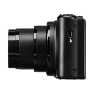 Mustan värinen Canon PowerShot SX740 HS -kompaktikamera, jonka objektiivi on ulosvedetty, kuvassa sivuttain valkoista taustaa vasten. Rungossa näkyy salamasymboli pienen painikkeen yläpuolella.