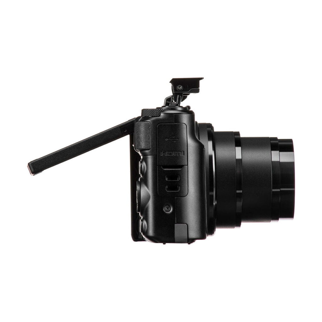 Canon PowerShot SX740 HS -kompaktikamera näytetään sivulta, jossa sen LCD-näyttö on käännetty ulos ja kulmassa, ponnahdussalama on nostettu ja objektiivi on täysin laajennettu.