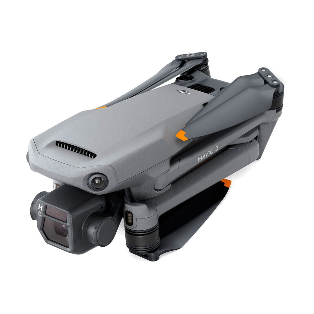 DJI_Mavic_3_Fly_More_Combo_011 Taitettu DJI Mavic 3 Fly More Combo -lennokki, jossa on Hasselblad-kamera, tyylikäs harmaa muotoilu ja oranssit käsivarren korostukset, näkyy sivulta valkoista taustaa vasten.