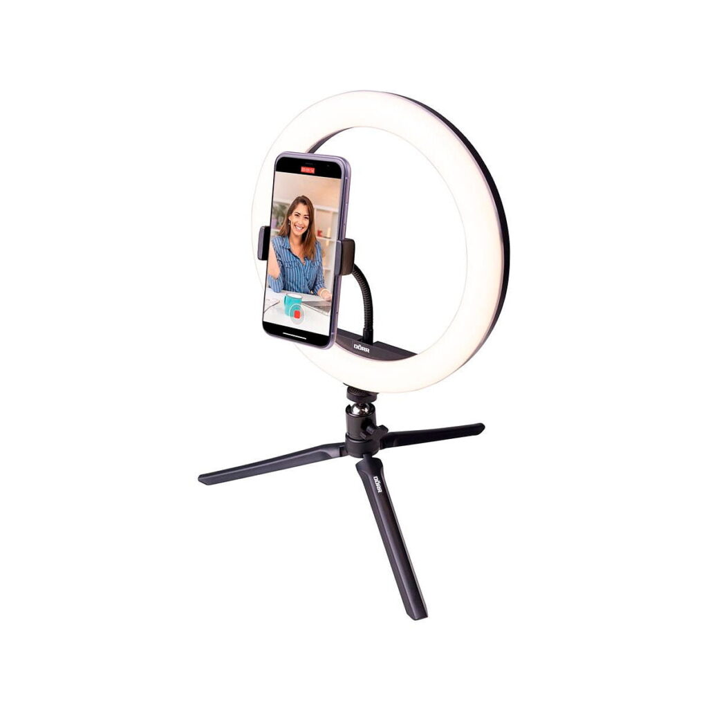 Dörr_VL-26_RGB_Vlogging_Kit_002 Dörr VL-26 RGB Rengasvalo Vlogging Kitissä on jalustalla oleva rengasvalo, jonka keskellä on älypuhelin, ja puhelimessa näkyy nainen hymyilemässä videopuhelun tai nauhoituksen aikana, kaikki valkoista taustaa vasten.
