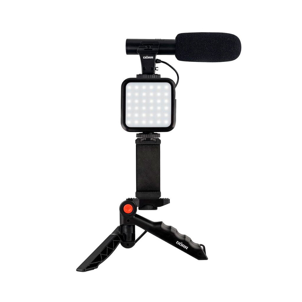 Dörr_VL-5_Vlogging_Kit_Mikrofonilla_001 Dörr VL-5 Vlogging Kit Mikrofonilla on kompakti kokoonpano, jossa on mikrofoni päällä, LED-valopaneeli keskellä ja älypuhelimen pidike, joka on kiinnitetty kannettavaan jalustaan.