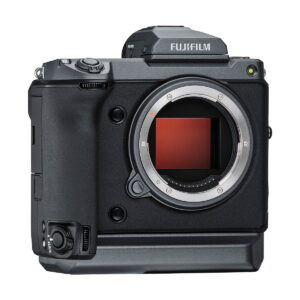 Fujifilm_GFX_100_001 Fujifilm GFX 100 on musta digitaalikameran runko, johon ei ole kiinnitetty objektiivia ja joka paljastaa kennon. Siinä on näkyvä vasemmanpuoleinen kahva sekä erilaisia ohjauspainikkeita ja valitsimia sen ylä- ja etupuolella.