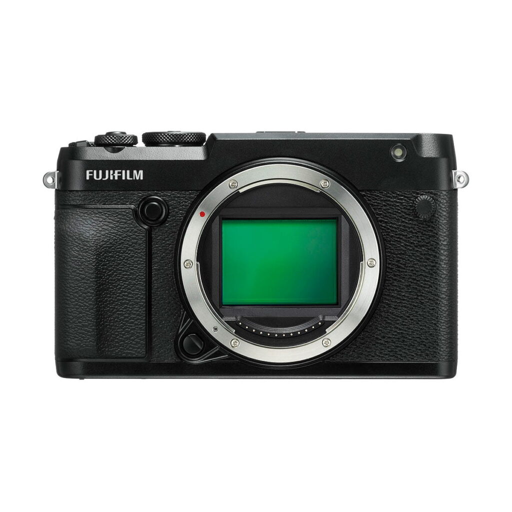 Fujifilm_GFX_50R_001 Musta Fujifilm GFX 50R -digitaalikameran runko ilman objektiivia, jossa korostuvat suuri kuvakenno ja yläosan säätöpyörät valkoista taustaa vasten kuvattuna.