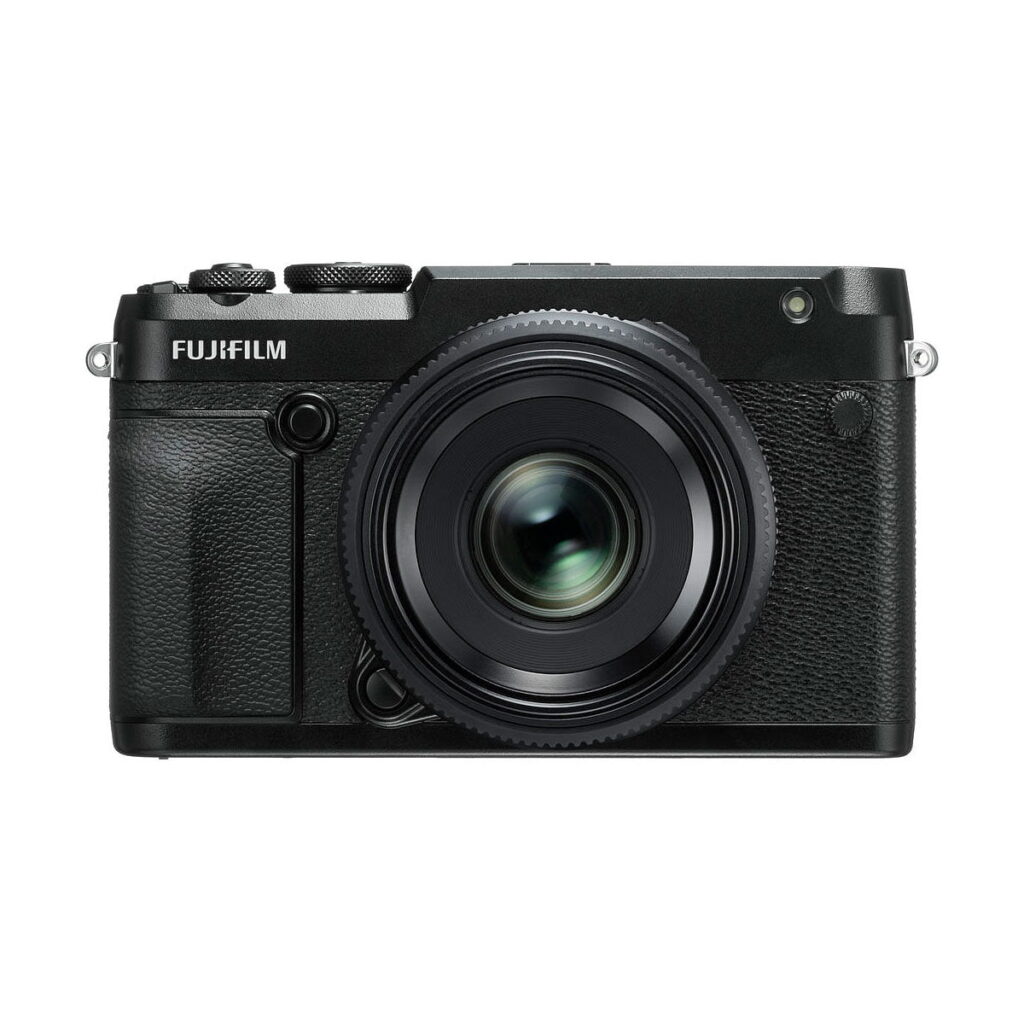 Fujifilm_GFX_50R_005 Mustan Fujifilm GFX 50R -digitaalikameran etukuva, jossa on kuvioitu kahva ja suuri objektiivi, keskitetty valkoiselle taustalle.
