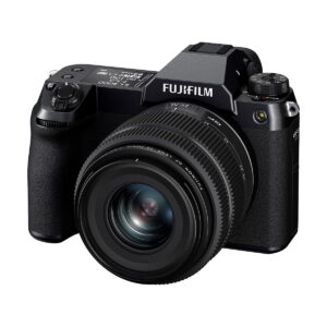 Fujifilm GFX 50S II, musta digitaalikamera, jossa on suuri irrotettava objektiivi ja useita säätöpyörästöjä, on kuvattu kolmivartalokulmasta valkoisella taustalla.