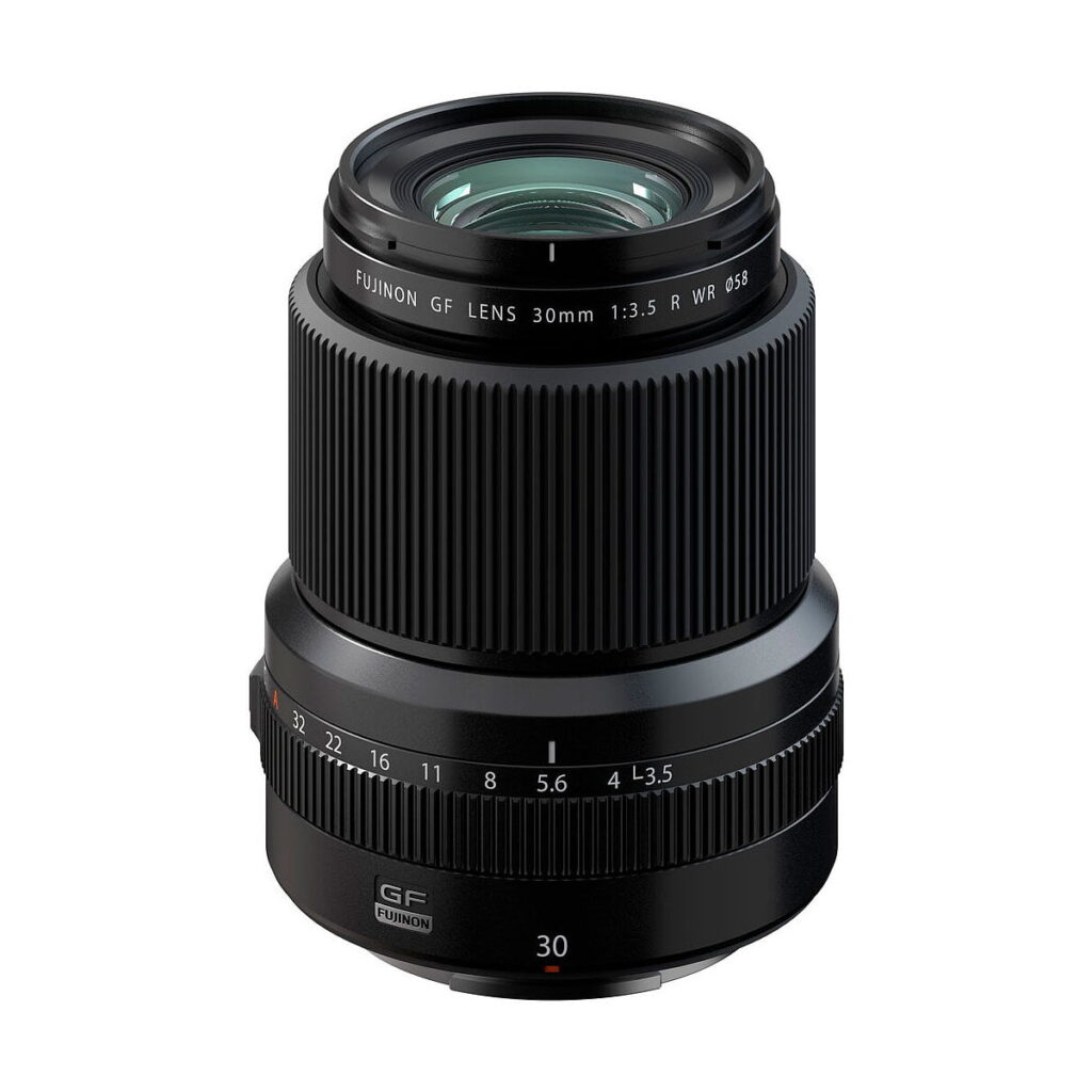 Fujifilm Fujinon GF 30mm f/3.5 R WR -objektiivi, jossa on aukkomerkinnät ja leveä tarkennusrengas, seisoo pystyssä tyylikkäässä mustassa muotoilussaan valkoista taustaa vasten.
