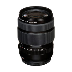 Fujinon_GF_32-64mm_f_4_R_LM_WR_003 A Fujifilm Fujinon GF 32-64mm f/4 R LM WR -objektiivi, musta kameran zoom-objektiivi teksturoiduilla tarkennus- ja zoom-renkailla, aukkomerkinnöillä ja 77 mm suodatinkierteellä, asetettuna pystysuoraan valkoista taustaa vasten.