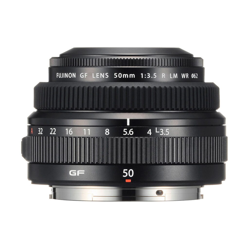 Fujinon_GF_50mm_f_3_5_R_LM_WR_004 Fujifilm Fujinon GF 50mm f/3.5 R LM WR -objektiivi näytetään edestä, ja siinä näkyy tarkennus- ja aukkorenkaat, yksityiskohtaiset objektiivin merkinnät ja hopeinen objektiivikiinnitys alareunassa.