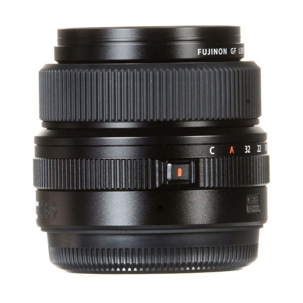 Fujinon_GF_63mm_2_8_R_WR_003 Musta Fujifilm Fujinon GF 63mm f/2.8 R WR -objektiivi, jossa on kuvioidut tarkennusrenkaat ja aukkorenkaat, aukkomerkinnät ja punainen merkkipiste sivussa valkoista taustaa vasten.