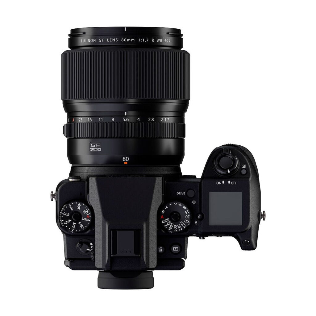Ylhäältä katsottuna Fujifilm-kamera, johon on asennettu Fujifilm Fujinon GF 80mm f/1.7 R WR -objektiivi, jossa korostuvat säätöpyörät, painikkeet ja digitaalinen näyttö oikealla puolella.