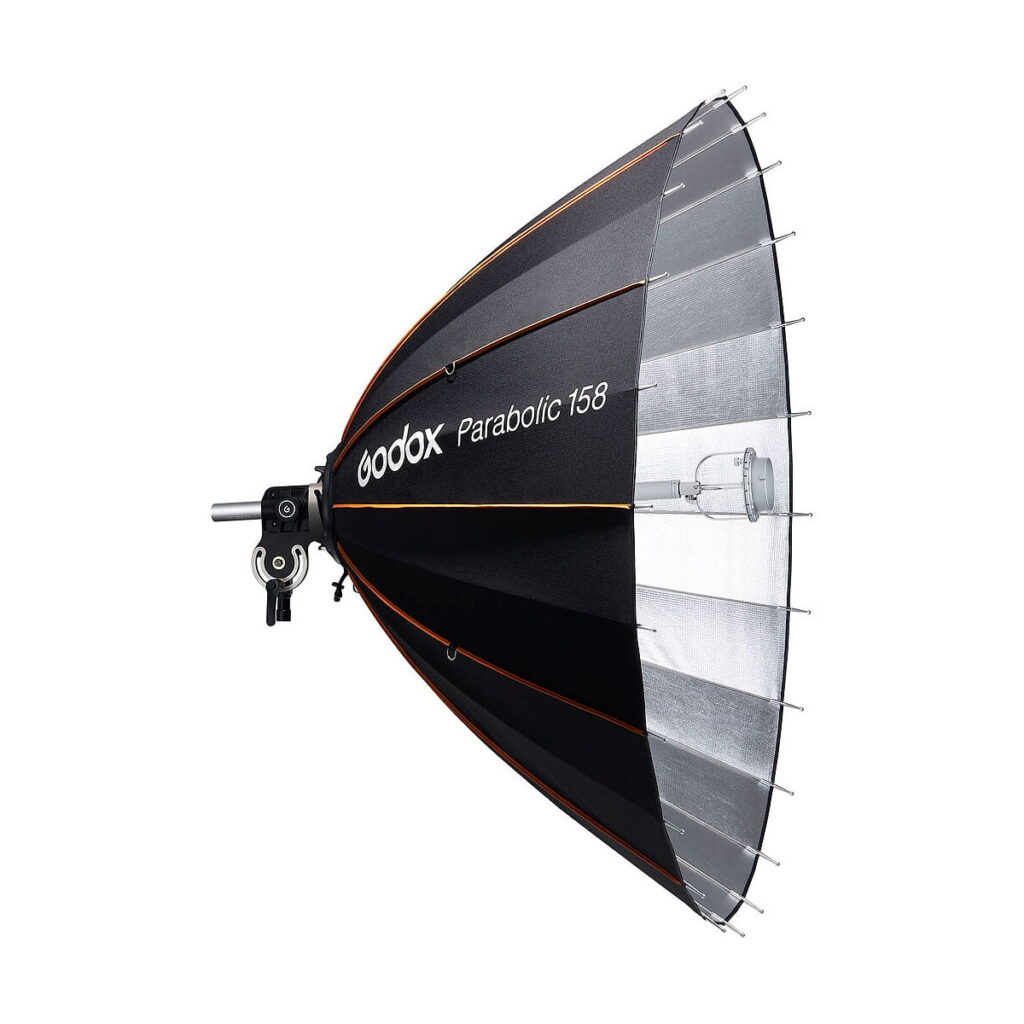 Godox_Parabolic_158_Reflector_Kit_001 The Godox Parabolic 158 Reflector Kit, a large black reflector with a silver interior, is mounted on a studio light bracket and displayed against a white background.
